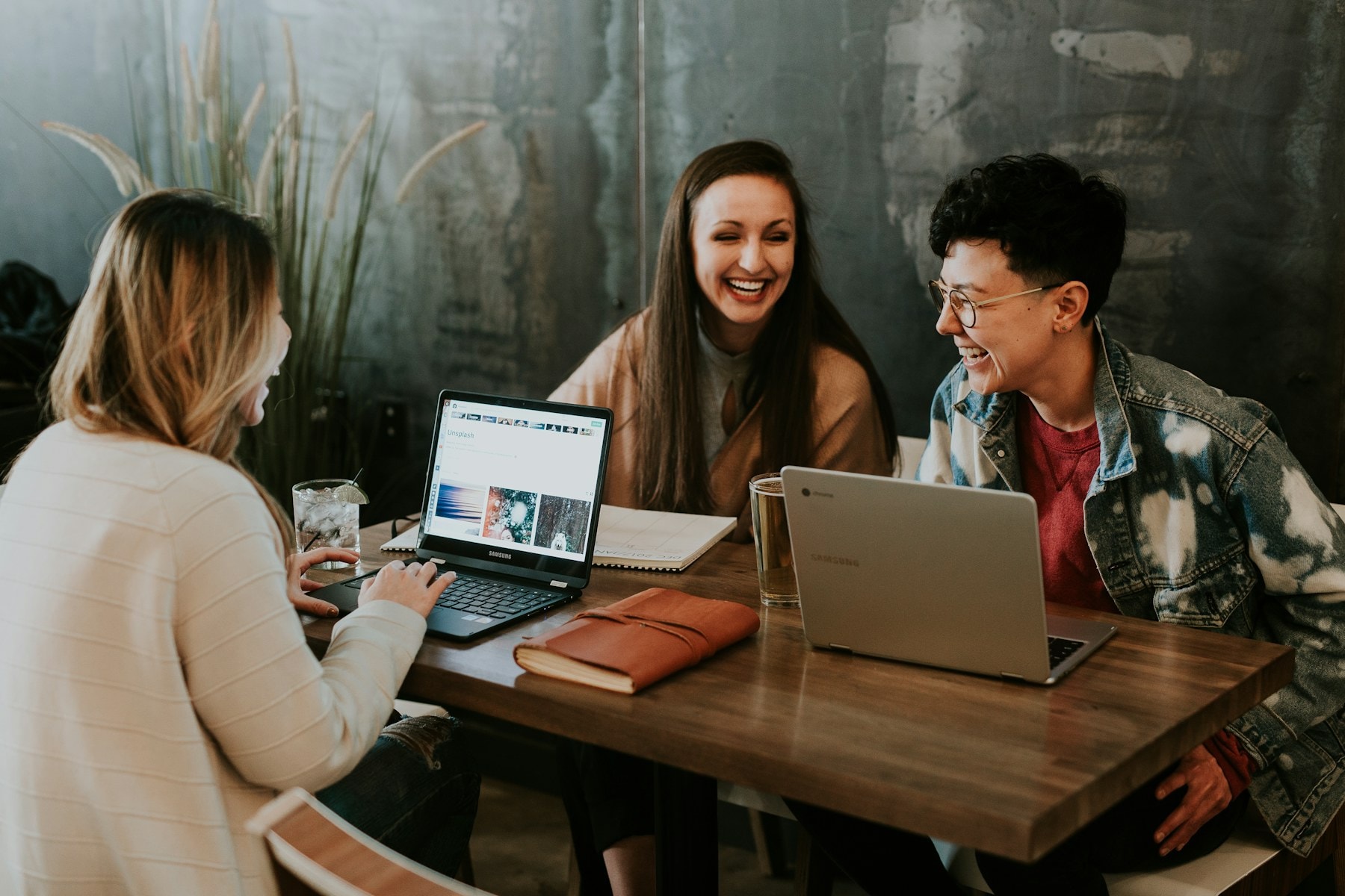 A small team working together around a table with laptops and notebooks